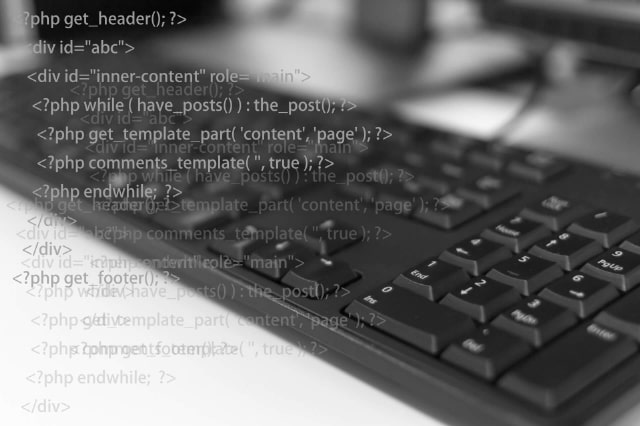 PCのキーボードとソースコードのイメージ